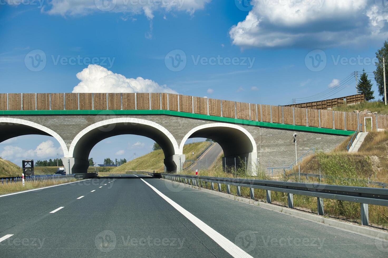 Modern highway with an overpass bridge on a sunny day with blue skies and white clouds photo