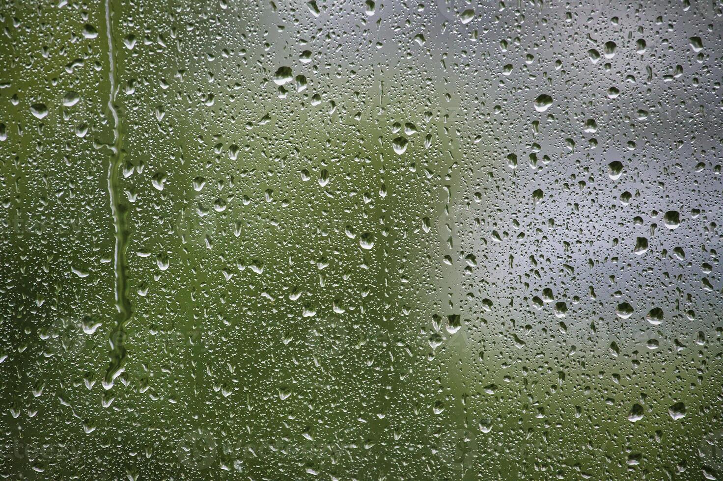 Window surface covered with many water droplets of various sizes, creating a textured pattern photo