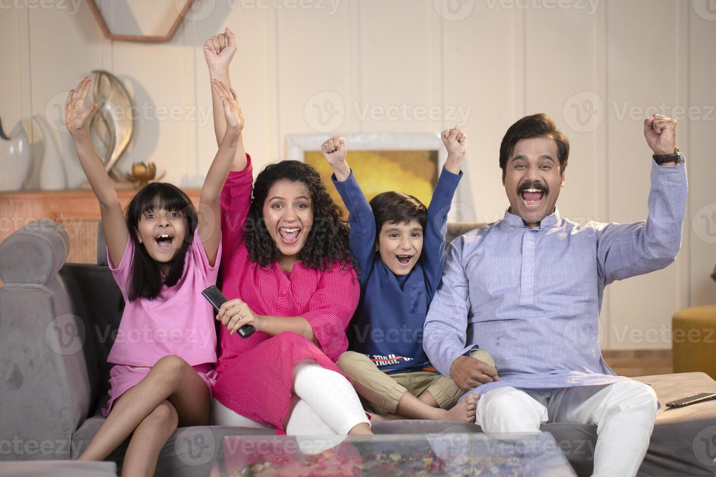 Family Sitting And Watching Cricket Match On Tv In Living Room photo