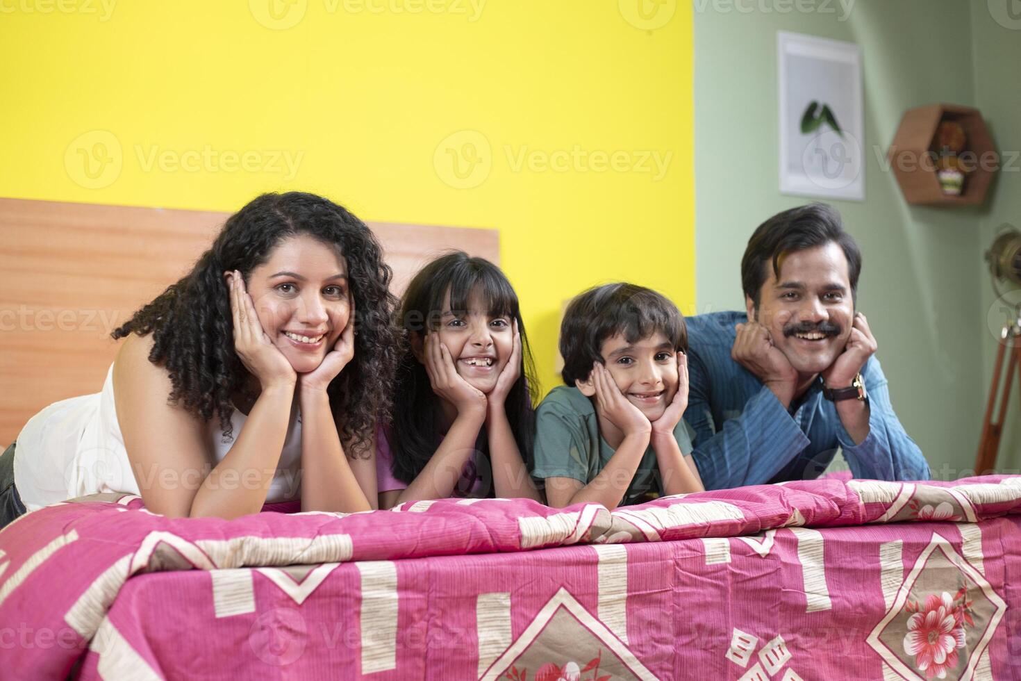 Joyful Family Lying On Bed Keeping Hand On Cheek photo