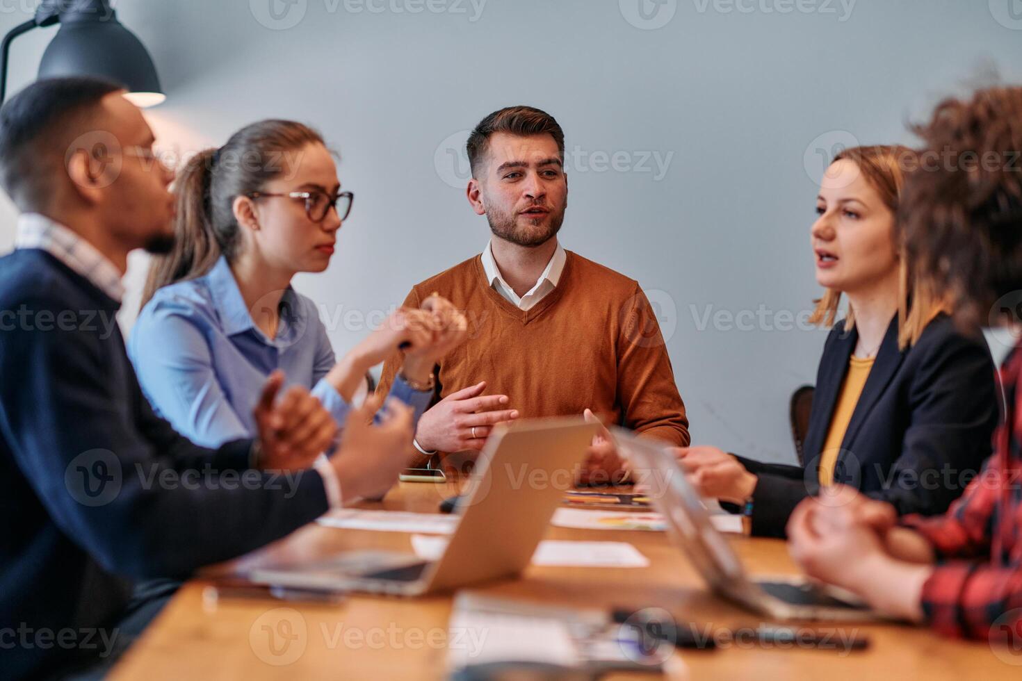 In the vibrant ambiance of a modern startup office, a diverse team of business professionals engage in discussions on various projects and develop new business strategies, epitomizing creativity and photo