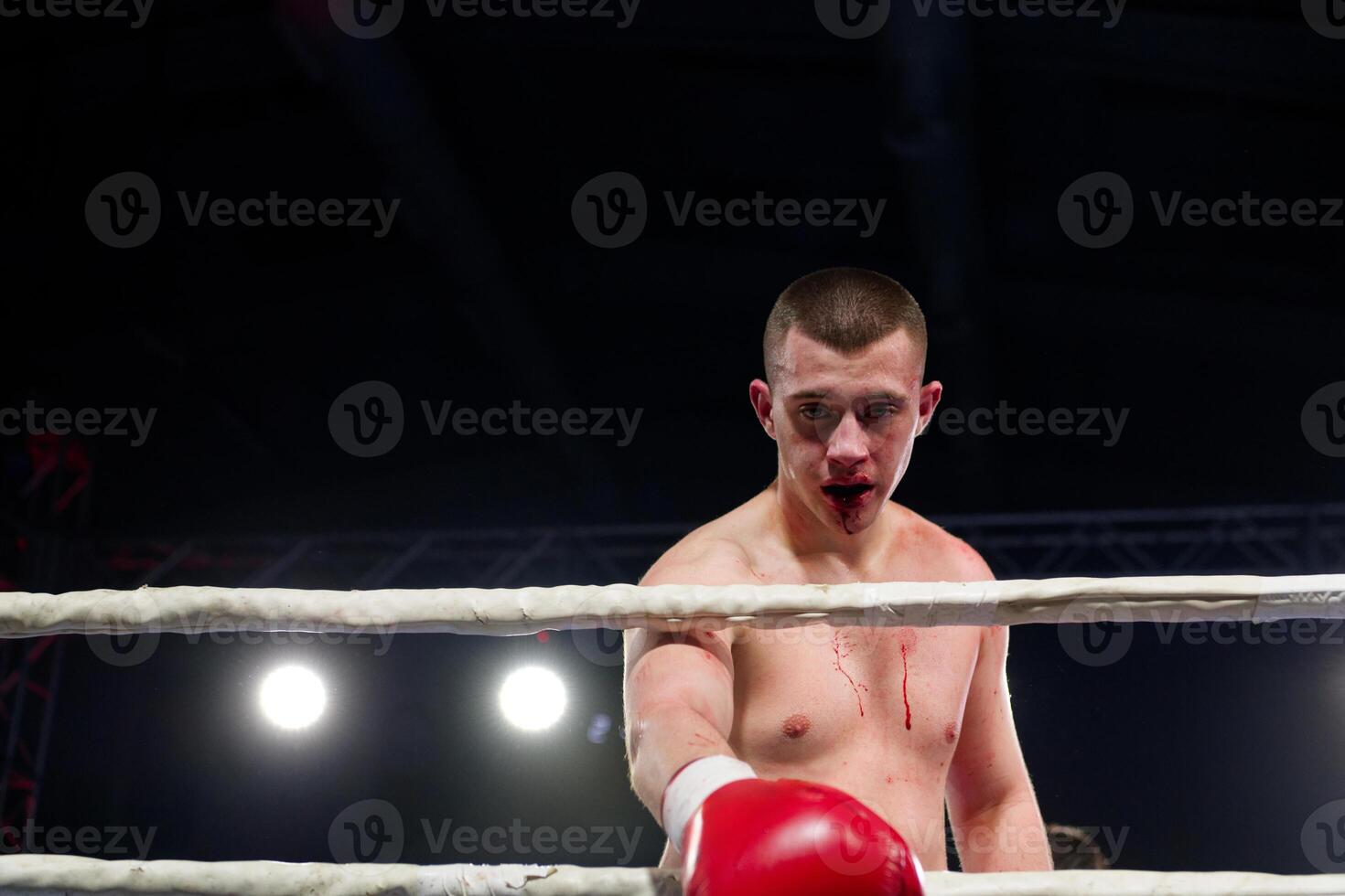 A bloodied boxer basks in the glory of victory, saluting the crowd after a grueling fight. photo