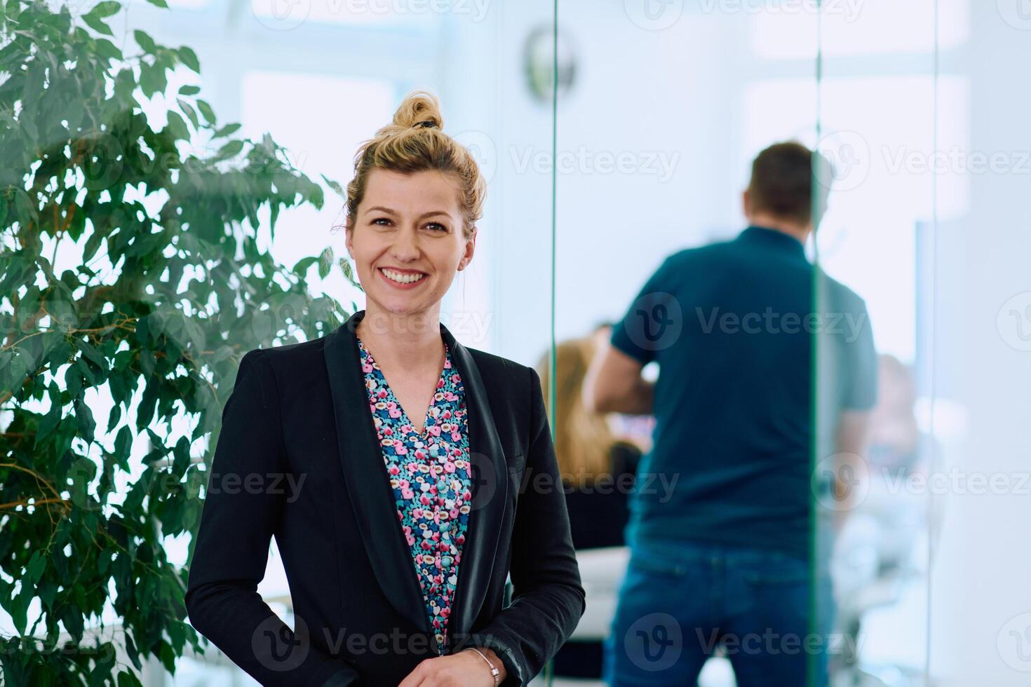 Portrait of a Blonde Businesswoman in a Modern Office with Her Workspace and Colleagues in the Background. photo
