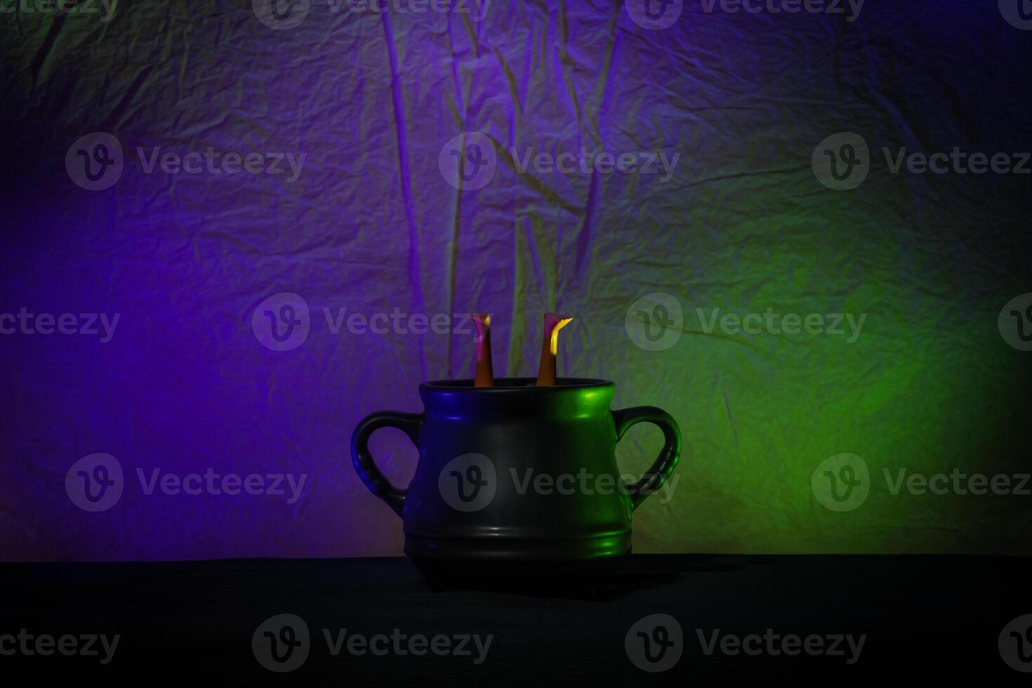 Black Cauldron With Witch Legs Under Colorful Neon Lighting photo