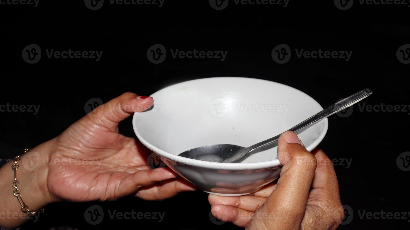 Hand holding empty white bowl with spoon photo