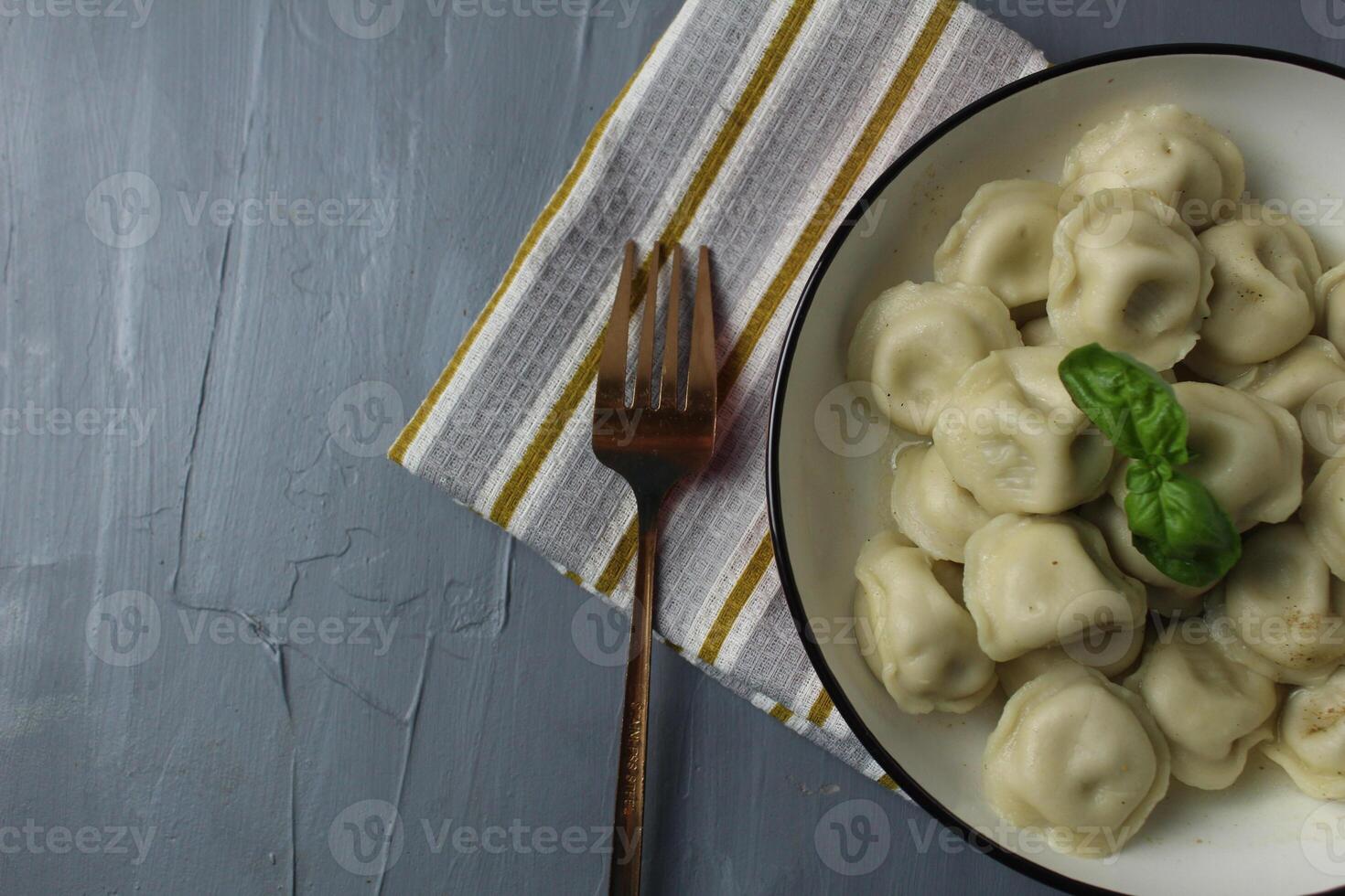Serving food with basil leaf with fork napkin dumplings in bowl bowl top view with space for copyspace recipe text photo