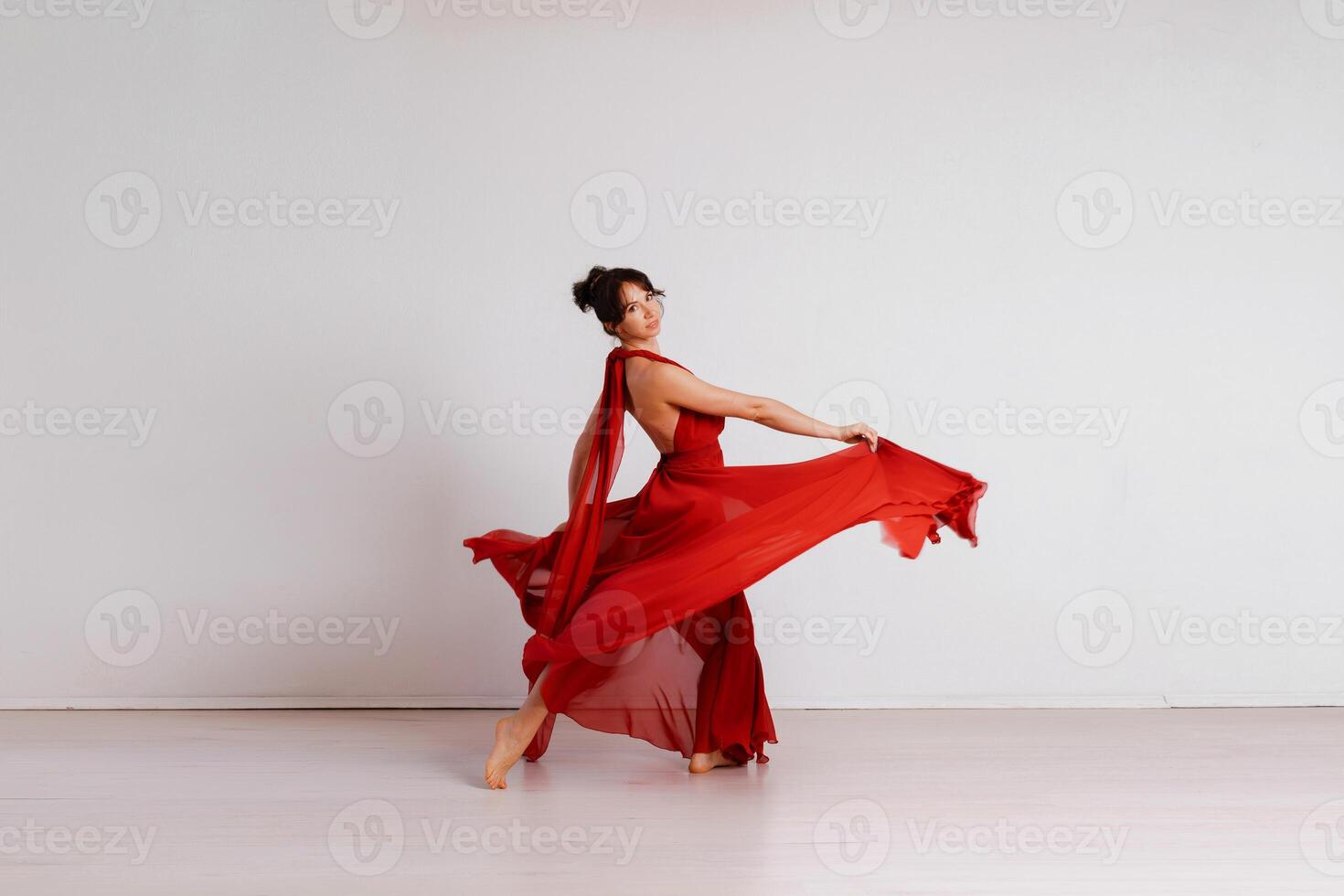 Dancer in a red flying dress. Woman ballerina dancing on a white studio background photo