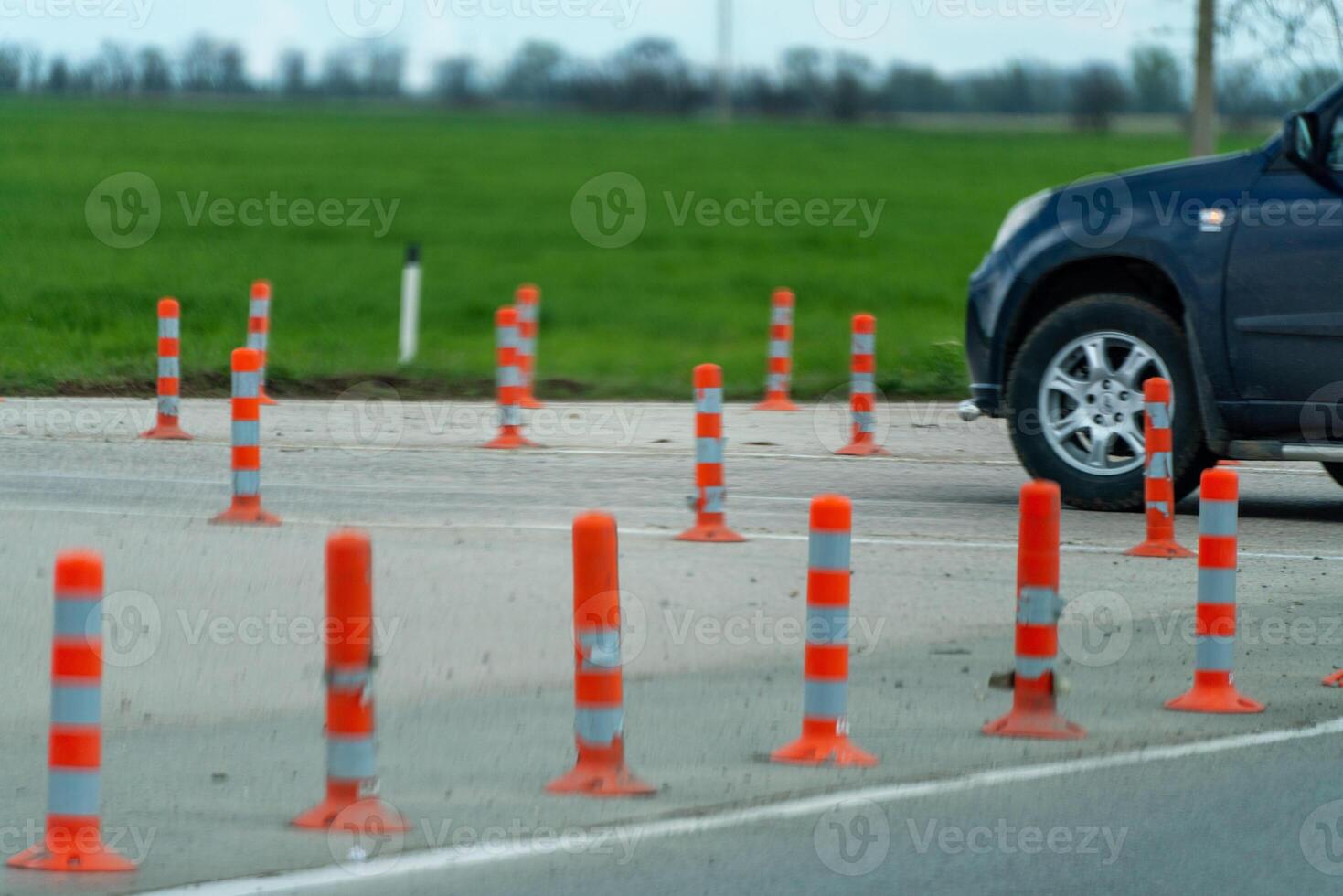 A row of orange and white traffic cones are lined up on a road. The scene is quiet and peaceful, with no cars or people in the area. photo
