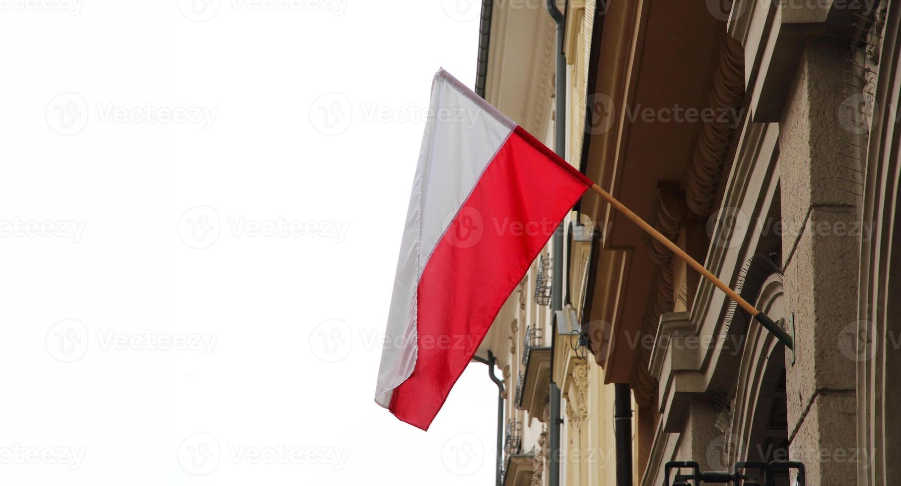 The Polish national flag flies on the facade of a building in the historic city, symbolizing patriotism. white background, banner with copy space photo