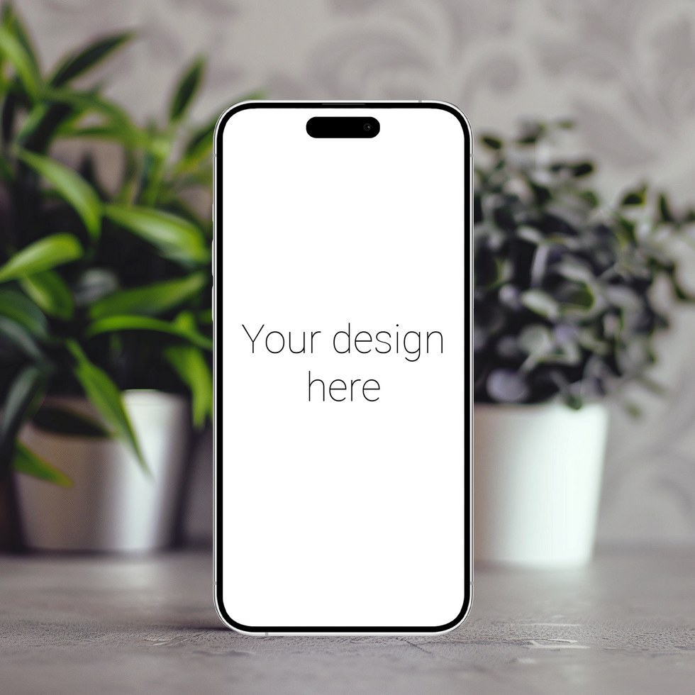 Mockup of white smartphone similar to iphone 15 that stands on table. There are plants nearby psd