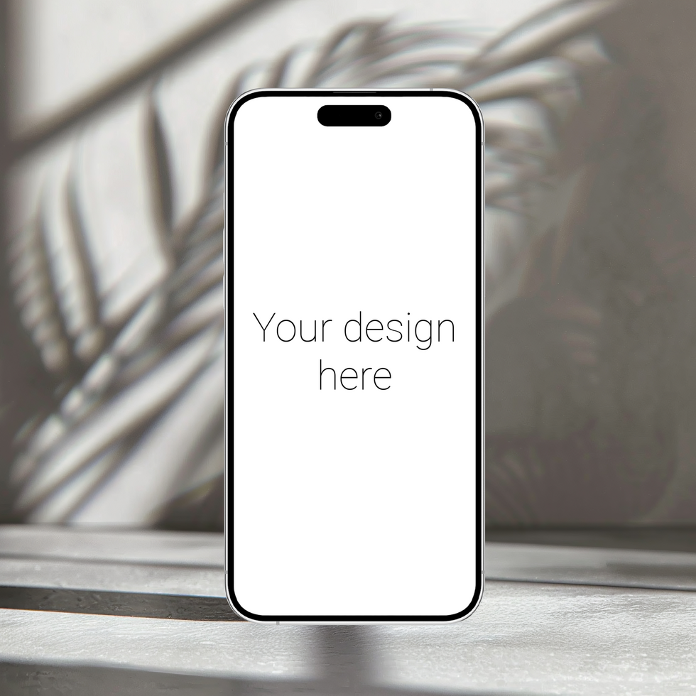 Mockup of white smartphone similar to iphone 15 that stands on table. There are plants nearby psd