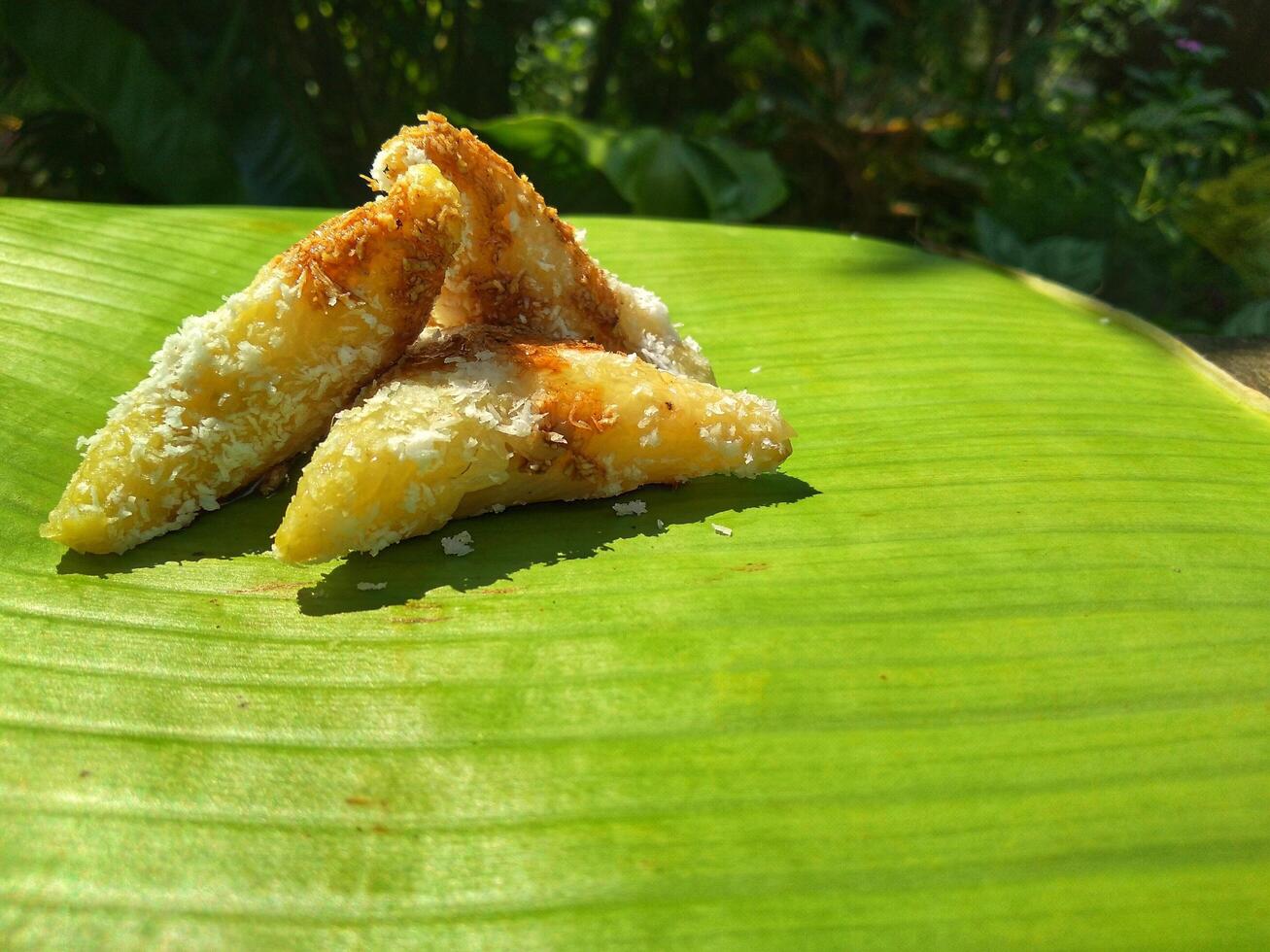 lupis cake is a traditional snack from Indonesia that has a soft and chewy texture made from glutinous rice that has a triangular shape served with grated coconut topping and sweet sauce, street food photo