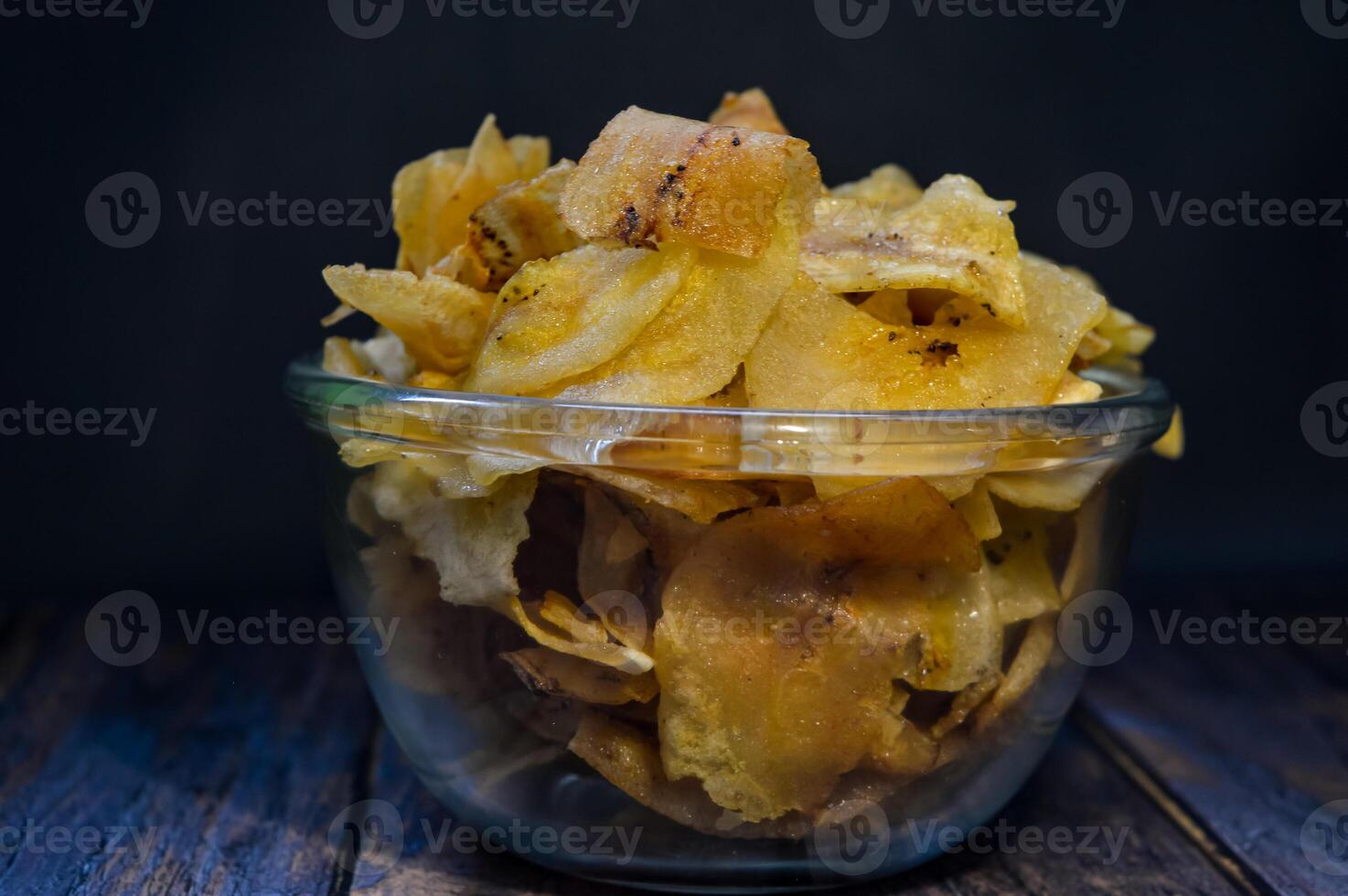 Keripik pisang or Banana crackers is a traditonal Indonesian snack. Made from banana and sugar. Sweet and crispy. with wooden background photo
