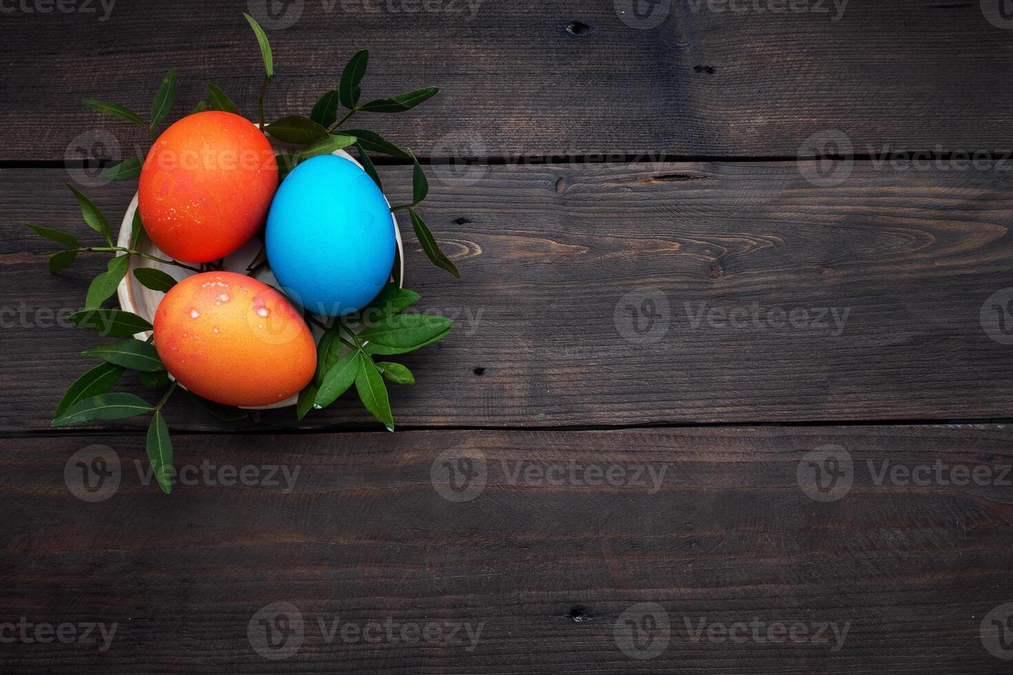 Easter eggs painted by hand colored on a dark wooden table, top view, copy space. photo