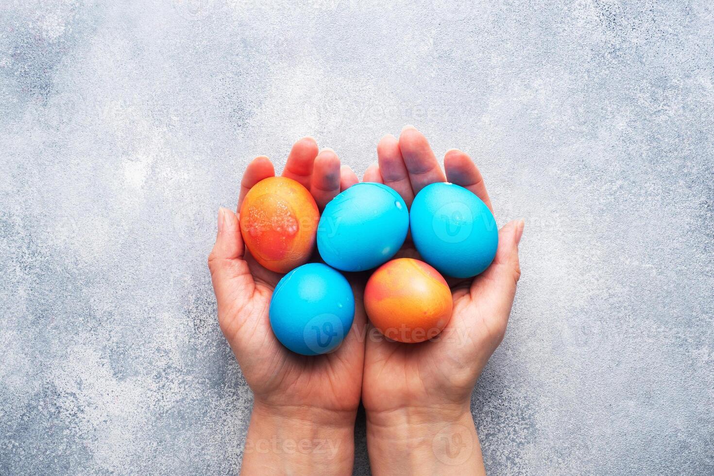 Easter eggs painted by hand colored on a concrete table, topview. copy space. In a woman's hands. photo