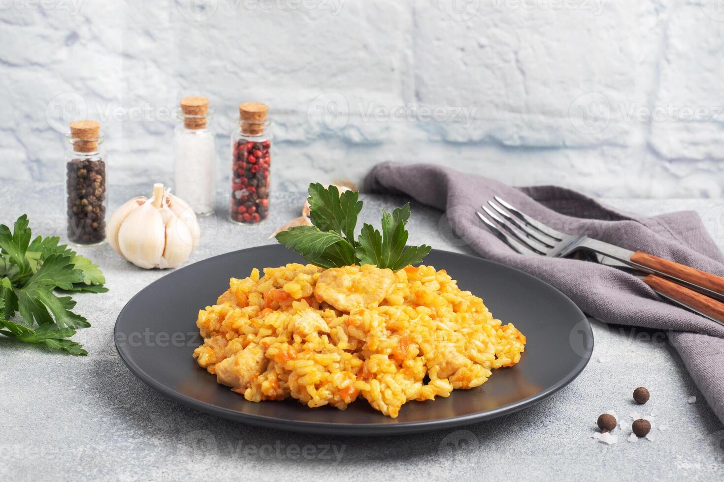 Delicious Asian pilaf, stewed rice with vegetables and chicken on a plate. gray concrete background. copy space. photo