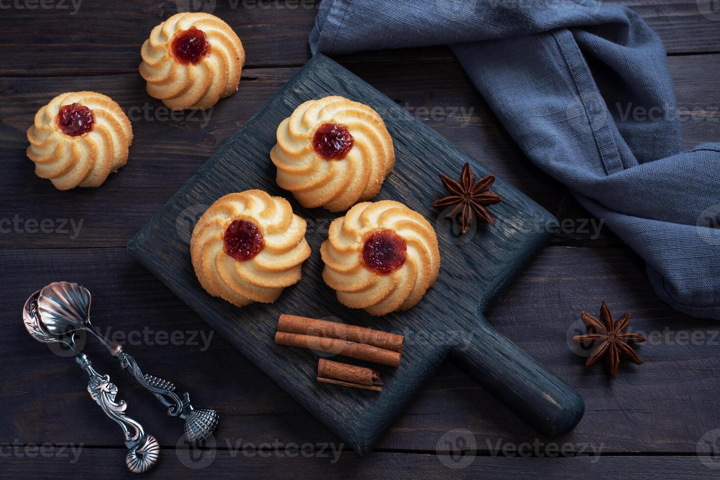 Kurabye shortbread cookies with berry jam in a black plate. Delicious dessert, dark wooden background with copy space. photo