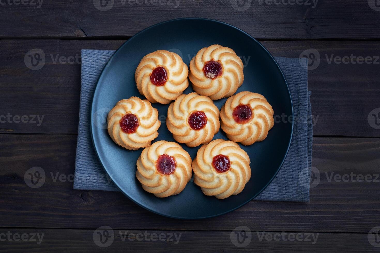 Kurabye shortbread cookies with berry jam in a black plate. Delicious dessert, dark wooden background with copy space. photo