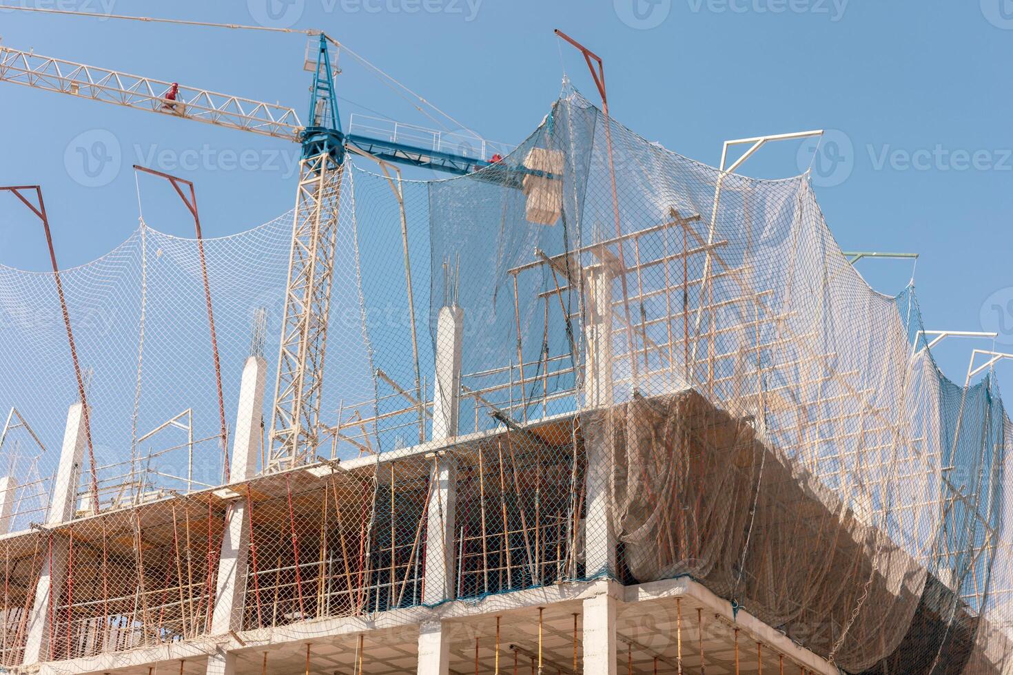 New building construction process. Safety nets and structural beams highlight ongoing work. Detailed shot of multi-level architecture. Ideal for articles on urban development, real estate investment. photo