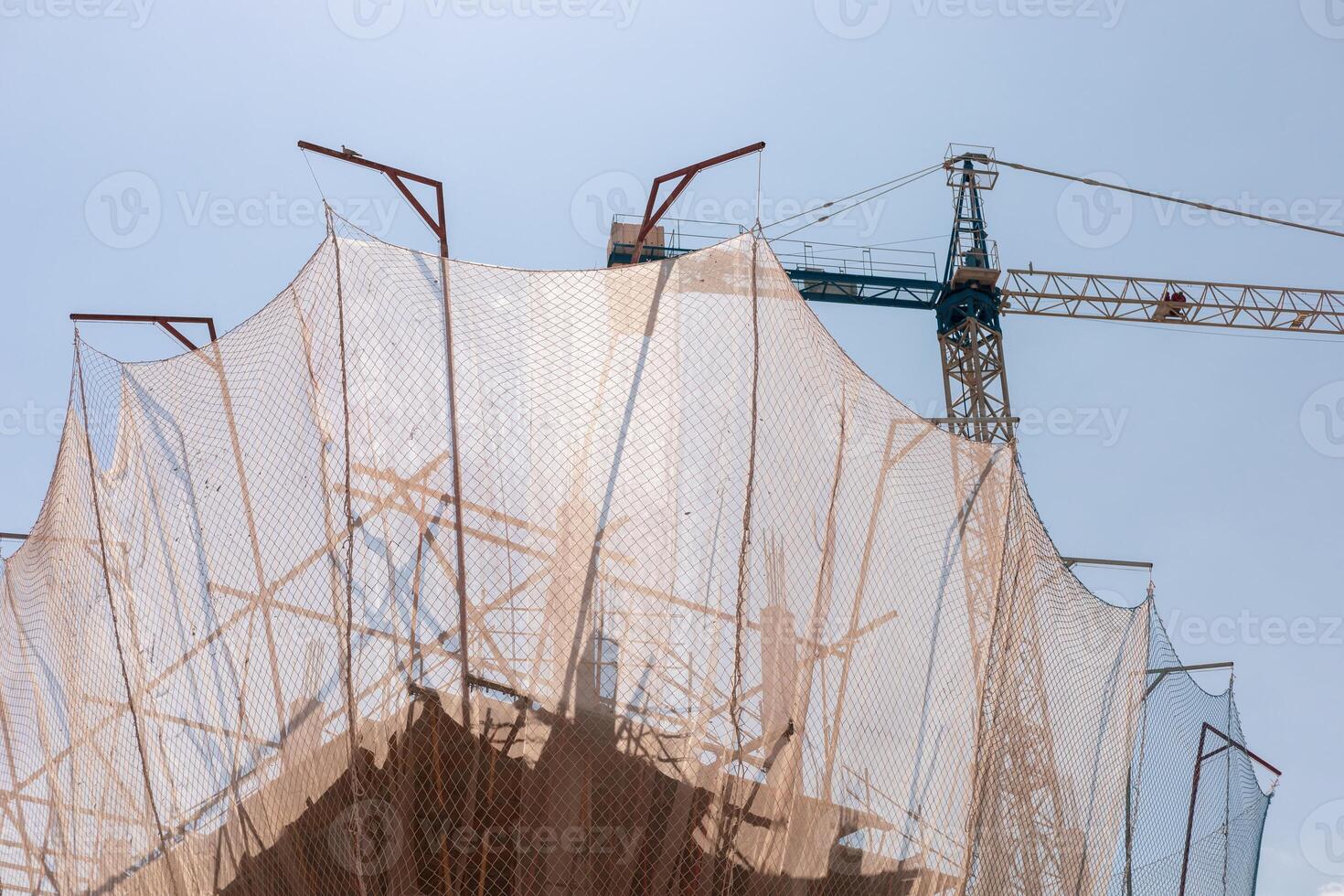 New building construction process. Safety nets and structural beams highlight ongoing work. Detailed shot of multi-level architecture. Ideal for articles on urban development, real estate investment. photo