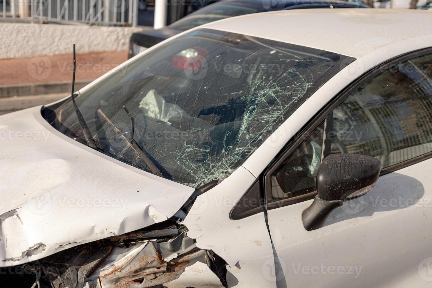 Close-up of car showing extensive front-end damage after collision, highlighting shattered windshield and deformed hood. Perfect for content on road safety, insurance claims, and automotive repairs. photo