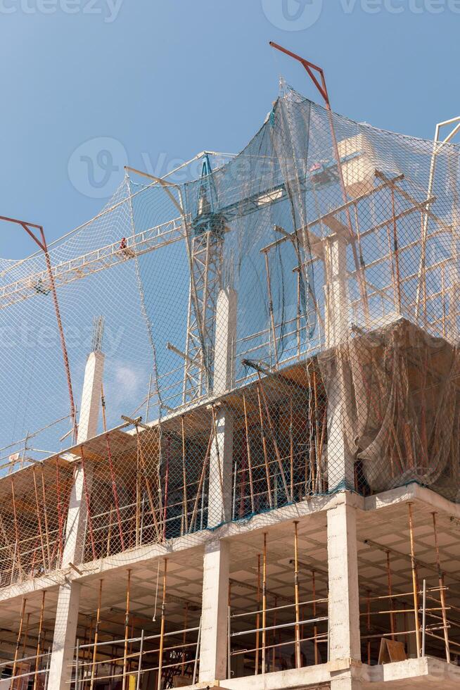 New building construction process. Safety nets and structural beams highlight ongoing work. Detailed shot of multi-level architecture. Ideal for articles on urban development, real estate investment. photo