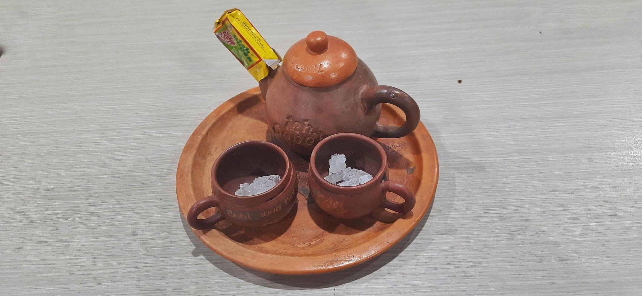 Teh Gopek or Teh Poci, traditional drink from Tegal City Central Java Indonesia. Set of Pottery Tea or Clay Pot with Rock Sugar. Bekasi, West Java, Indonesia - June 10 2024 photo