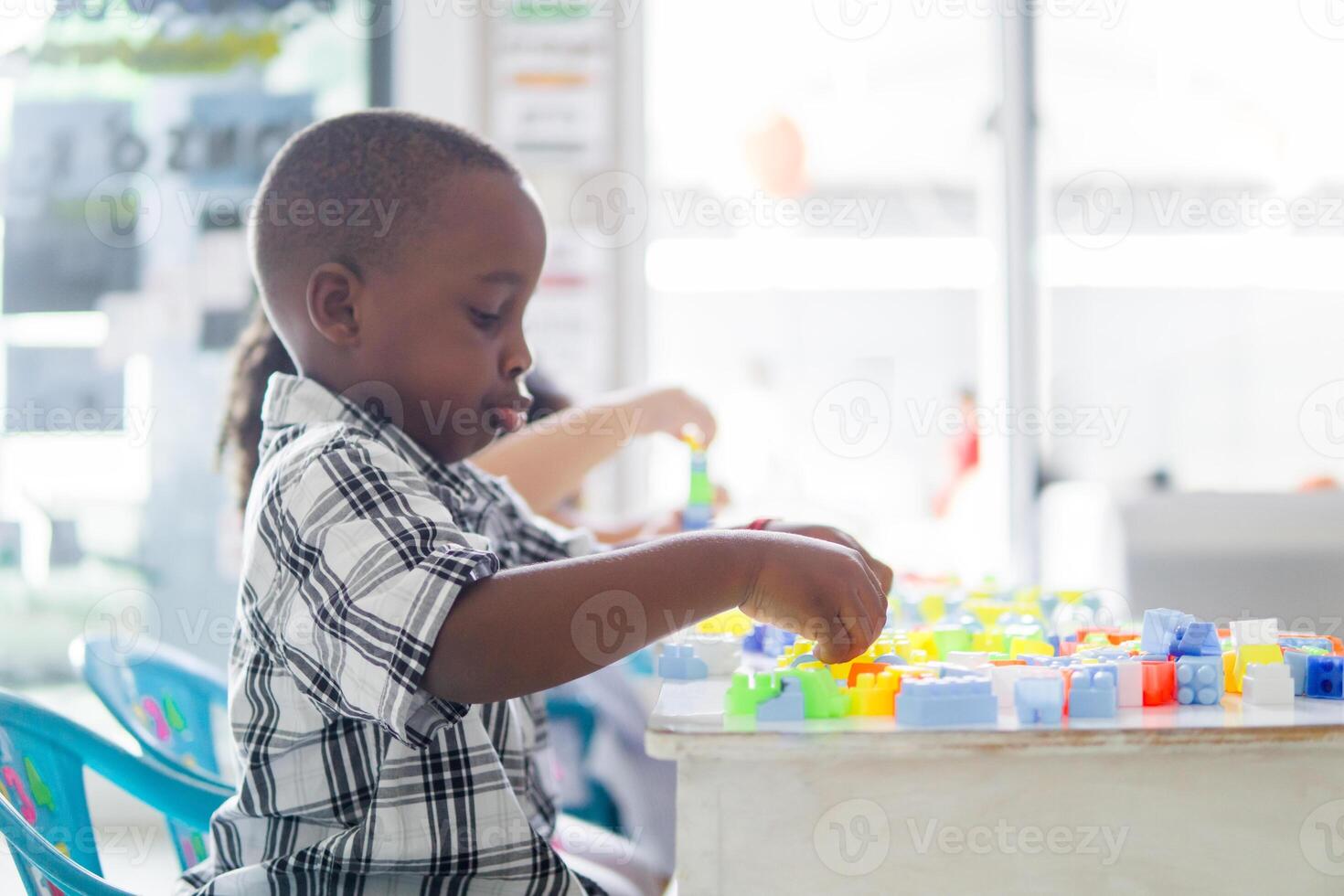 Portrait side view of little african boy enjoying with colored blocks. photo