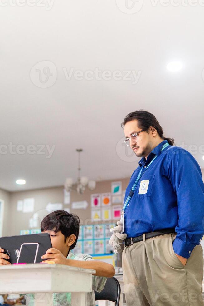 Teacher in class teaching student how use a laptop. photo