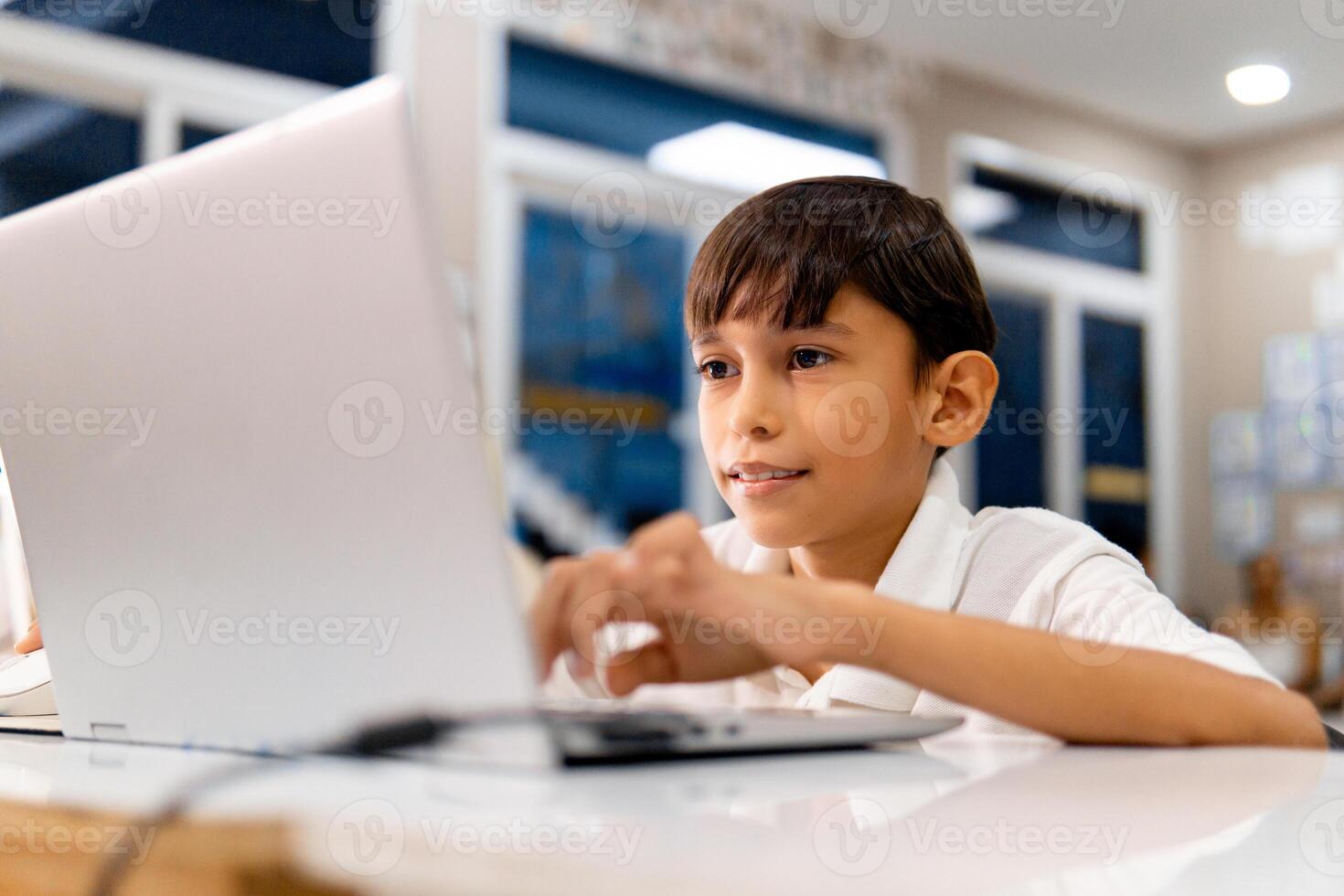 Portrait school boy using digital device in school classroom. photo