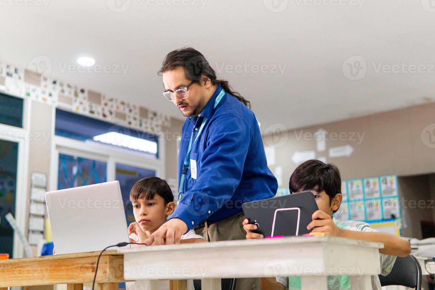 Teacher in class teaching student how use a laptop. photo