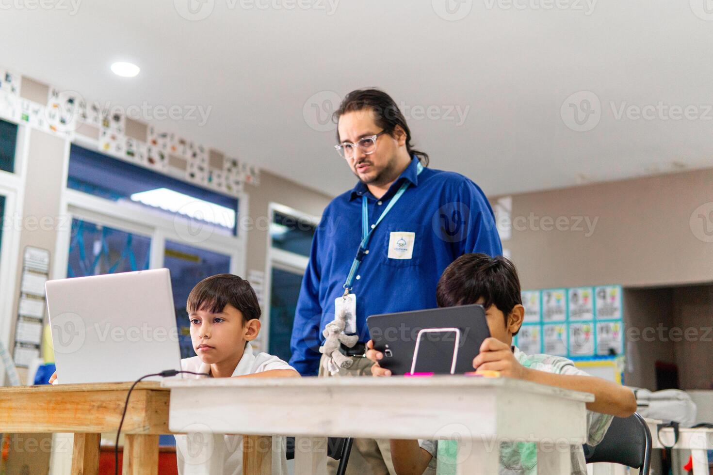 Teacher in class teaching student how use a laptop. photo