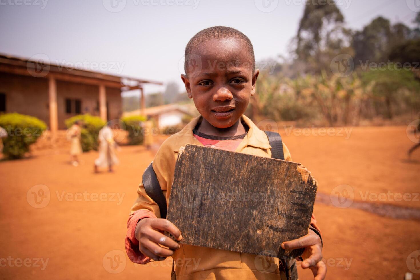 Little black child standing with his clean blackboard ready to write something on it photo