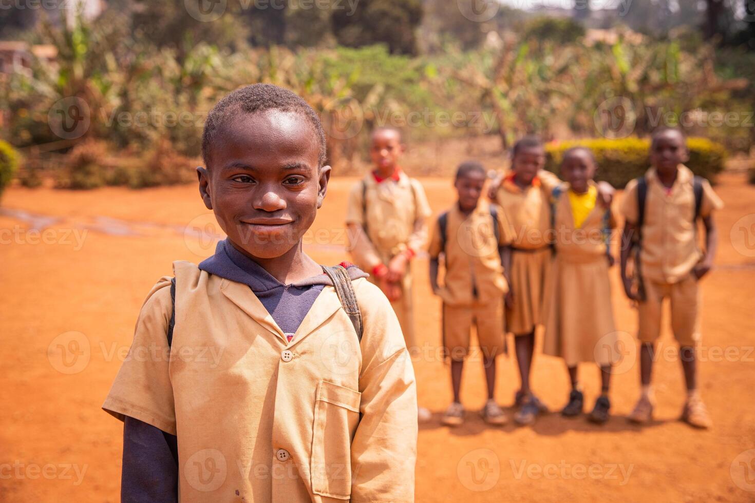 African schoolboy with Down syndrome in the schoolyard with his school mates out of focus in the background. photo