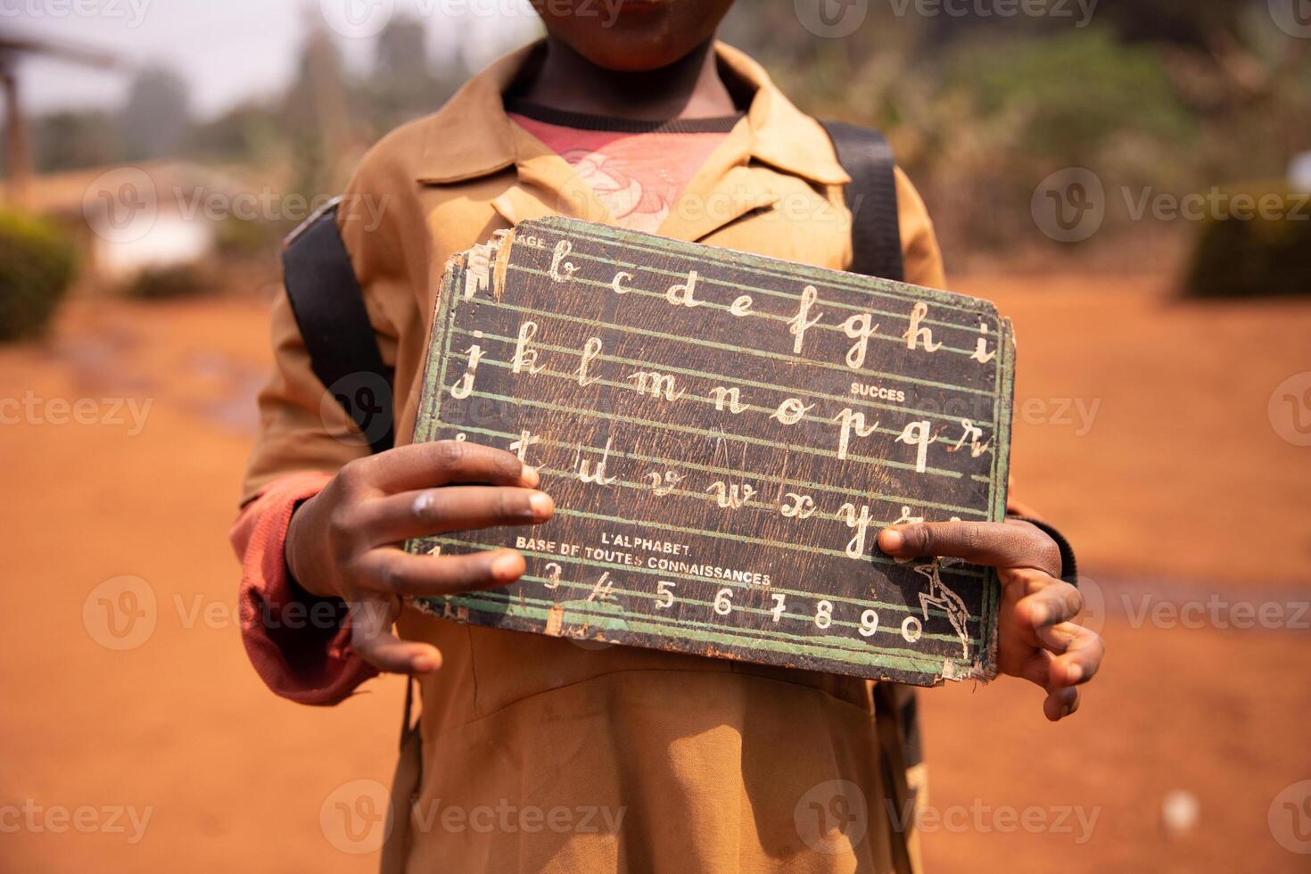 African child shows his blackboard with alphabet and the numbers engraved on it. Educational concept photo