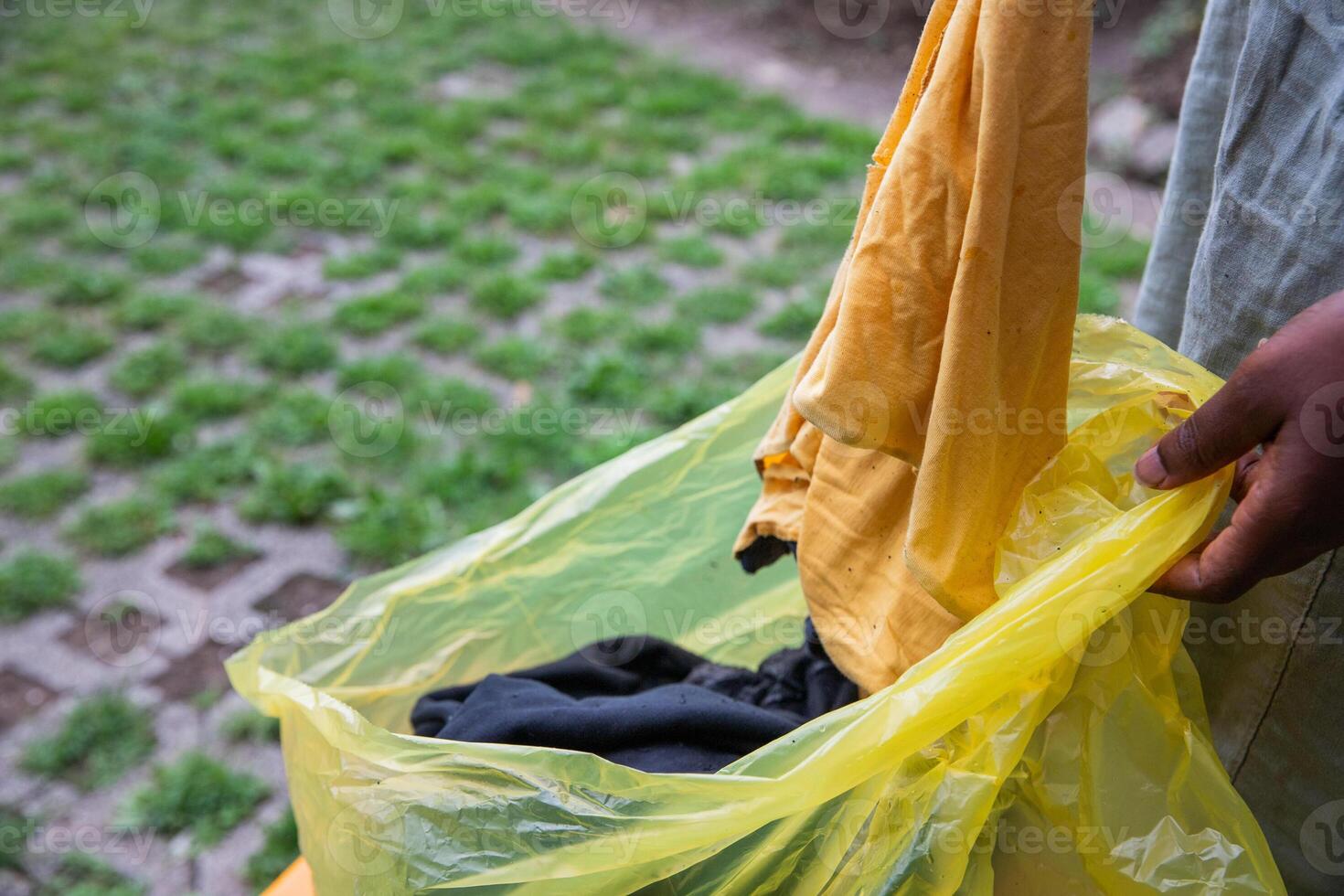A woman throws used clothes into a recycling bag, waste sorting in order not to pollute photo