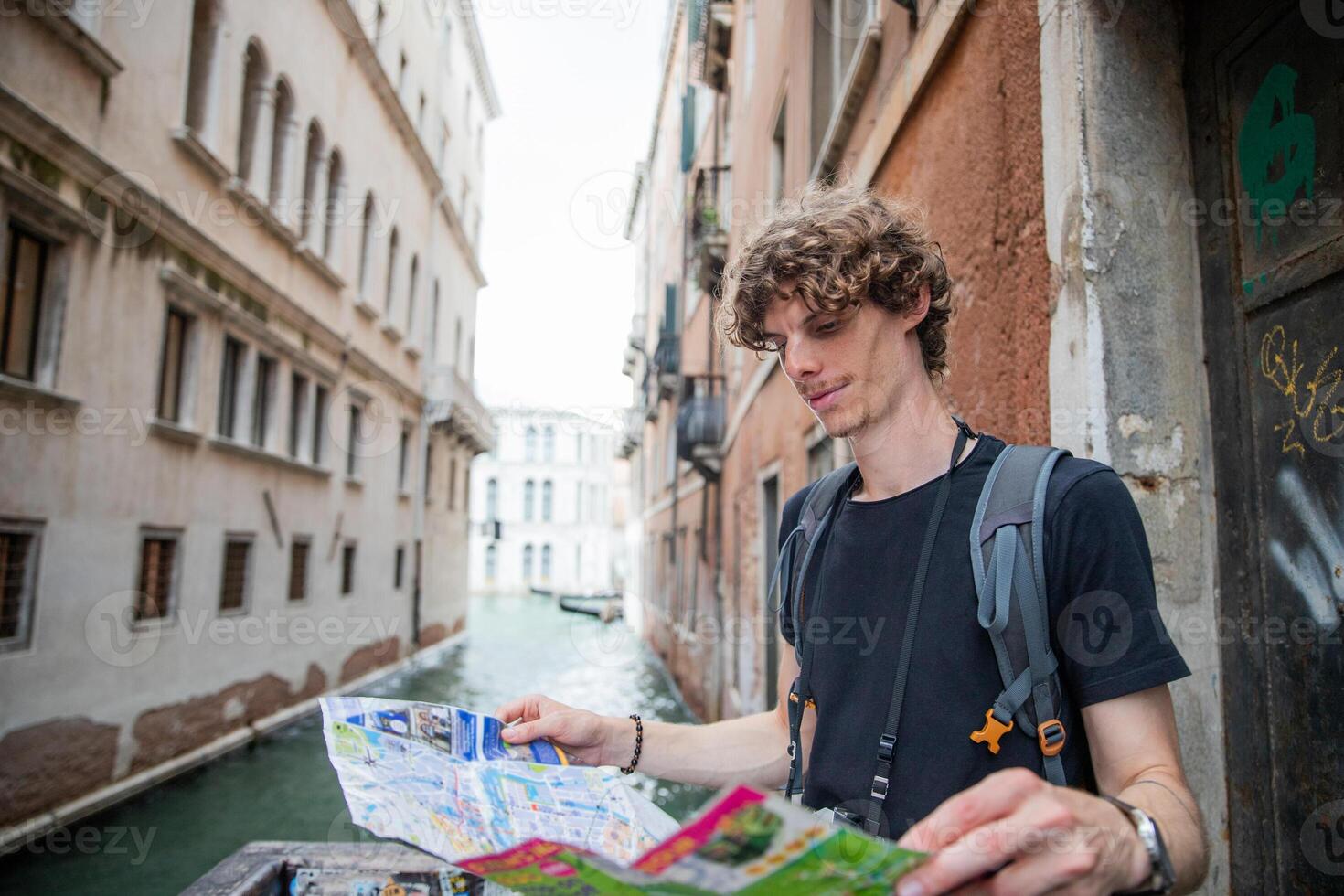 A tourist looks at the paper map of Venice as he visits the city photo