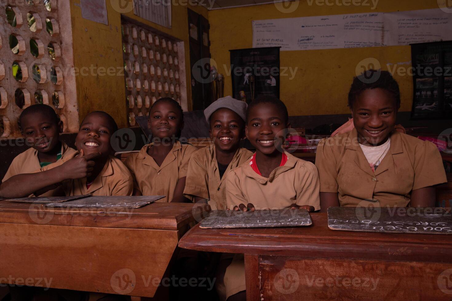 Group of pupils sitting at school desks with their blackboards happy laughing photo