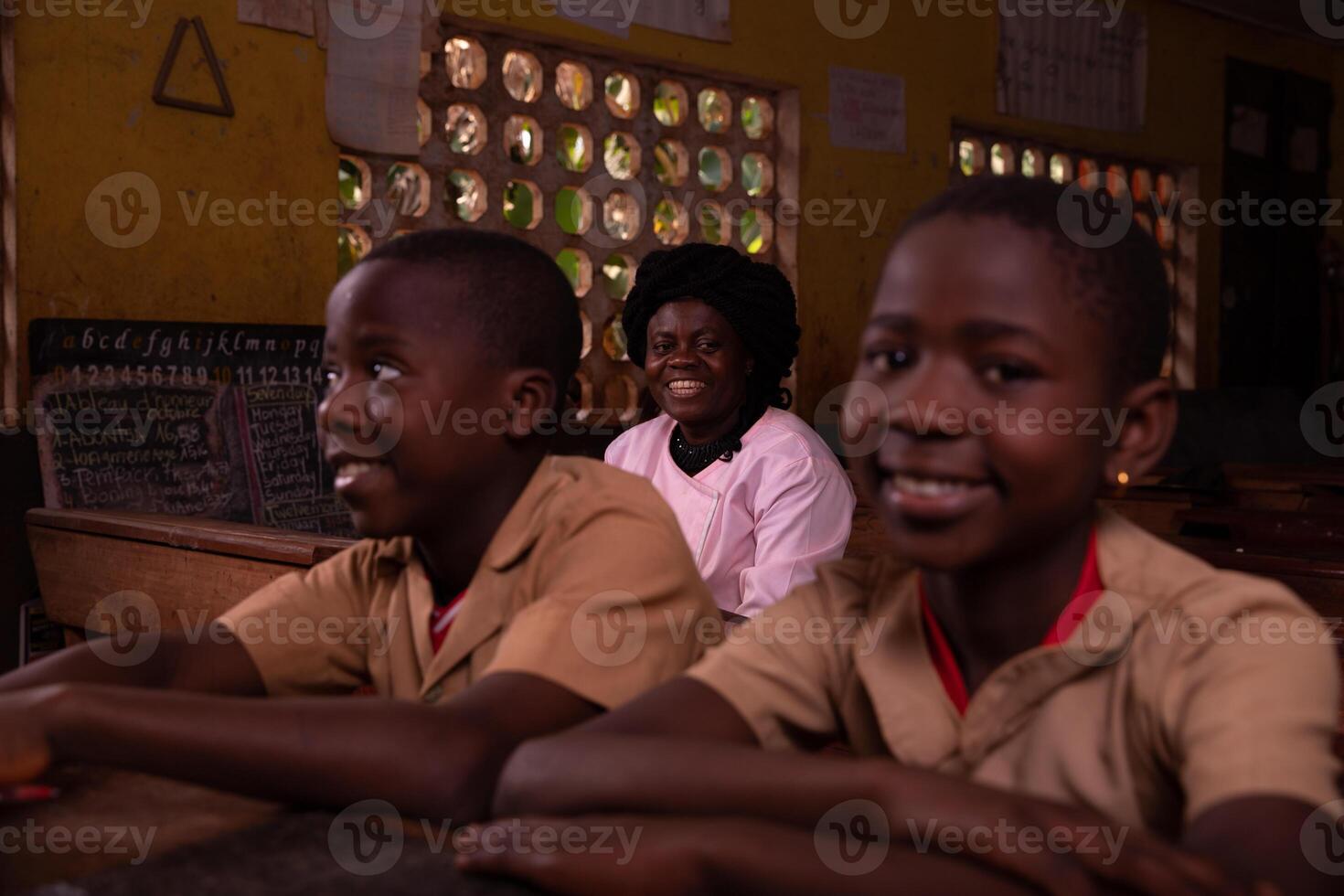 African teacher sitting in the classroom with her pupils photo