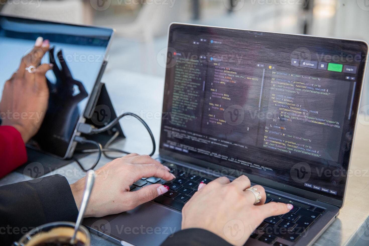 Female programmer writes some code and drinks coffee while sitting near her colleague. photo