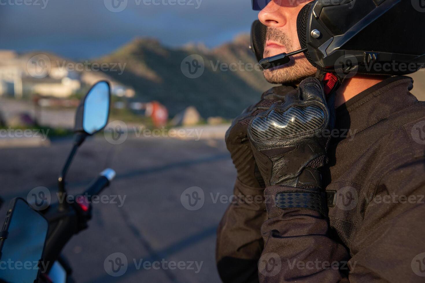 A motorcyclist puts on his helmet while sitting on his motorcycle. photo
