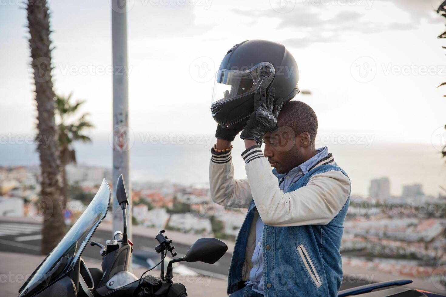 African American motorcyclist wears a helmet while sitting on his motorcycle photo