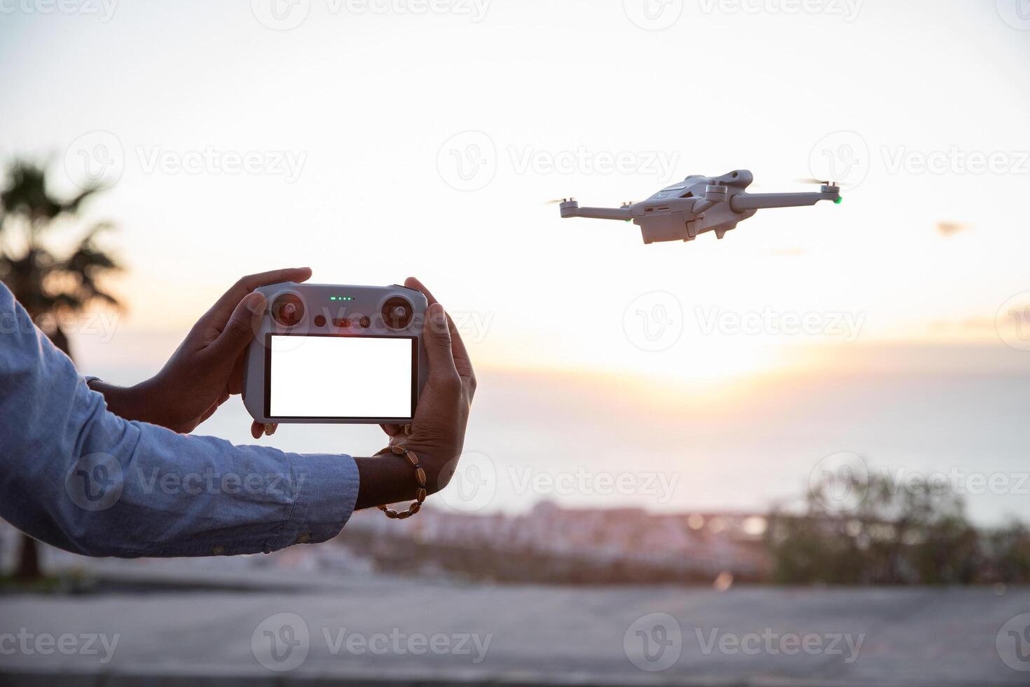 Close up on drone remote control with blank screen for mockup, drone flying beside. photo