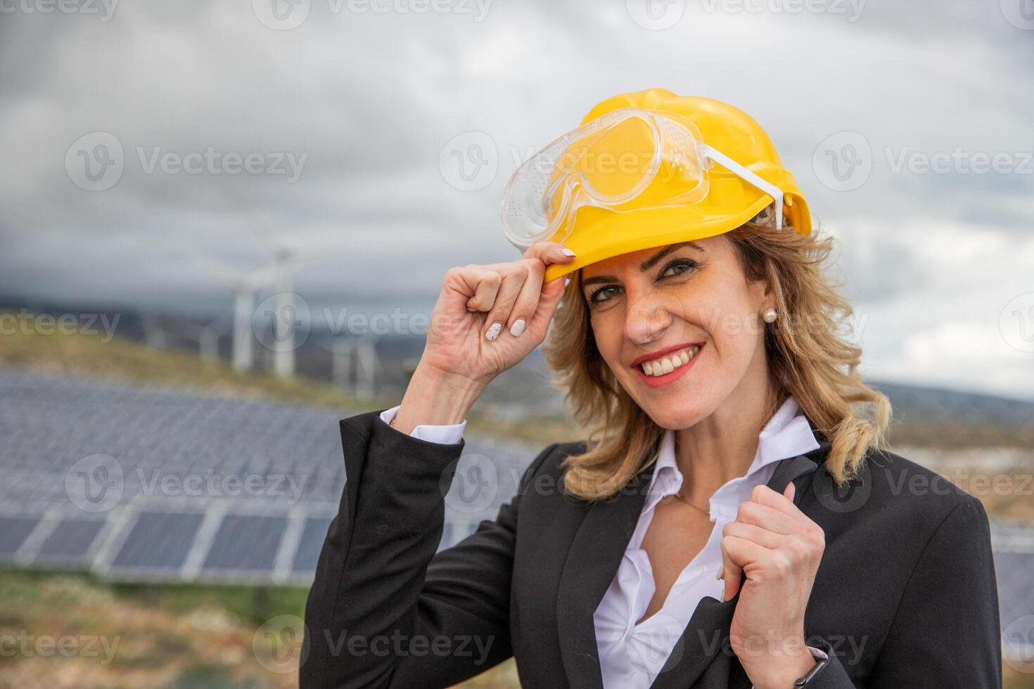 A smiling female engineer wears a protective helmet at at a solar power plant. photo