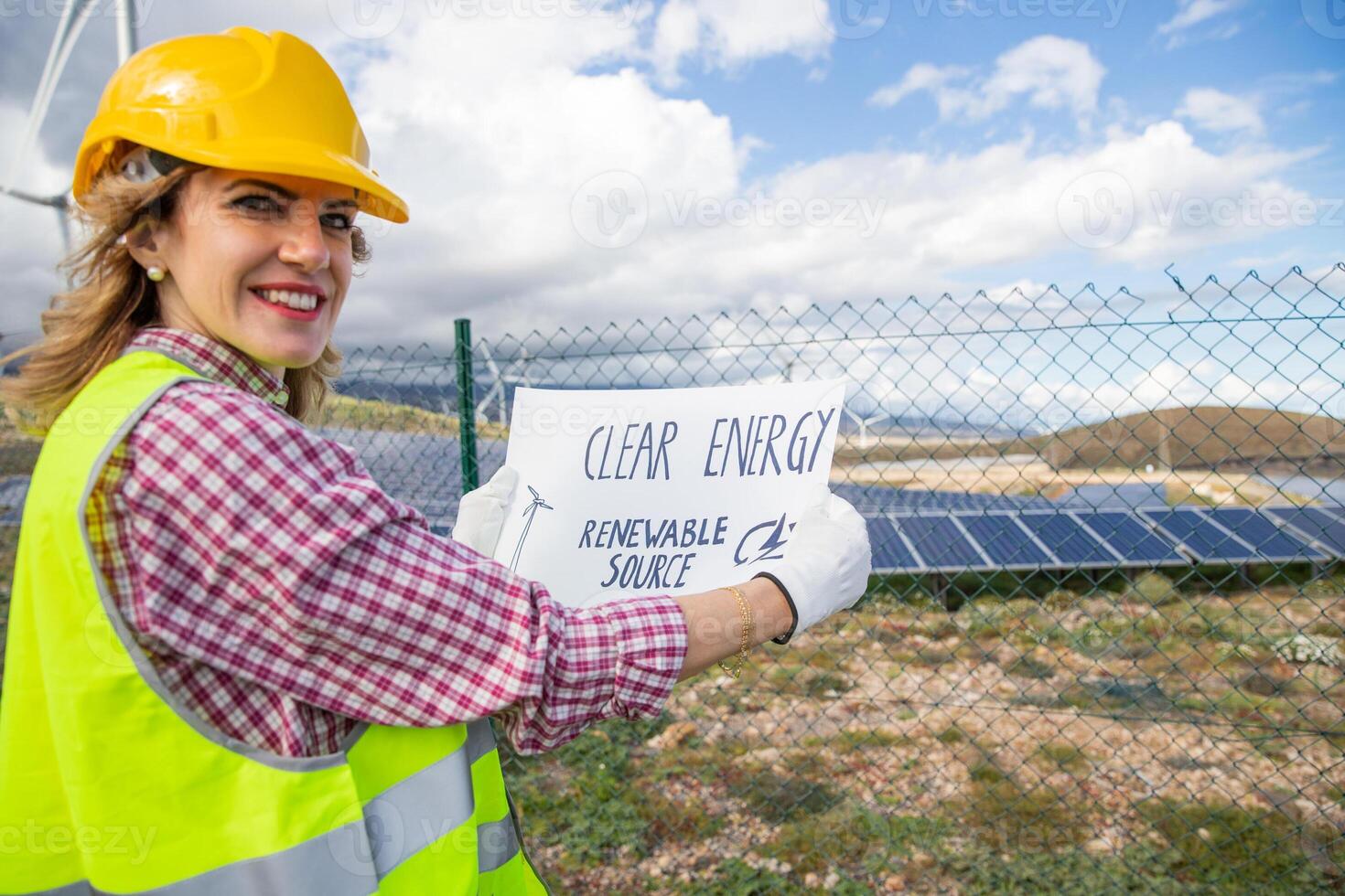 A female engineer at a solar power plant with a sheet that says clean energy renewable source photo