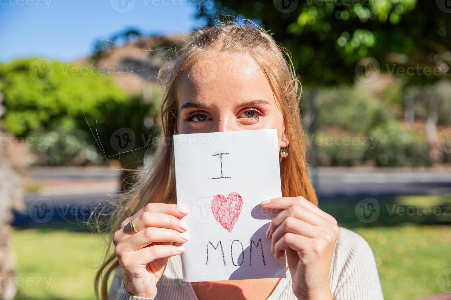 A woman is holding a card that says I love you mom photo