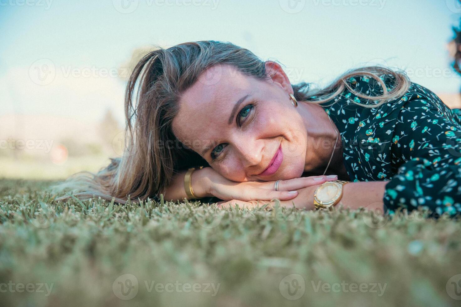 Portrait of a smiling woman with blue eyes lying on a meadow photo