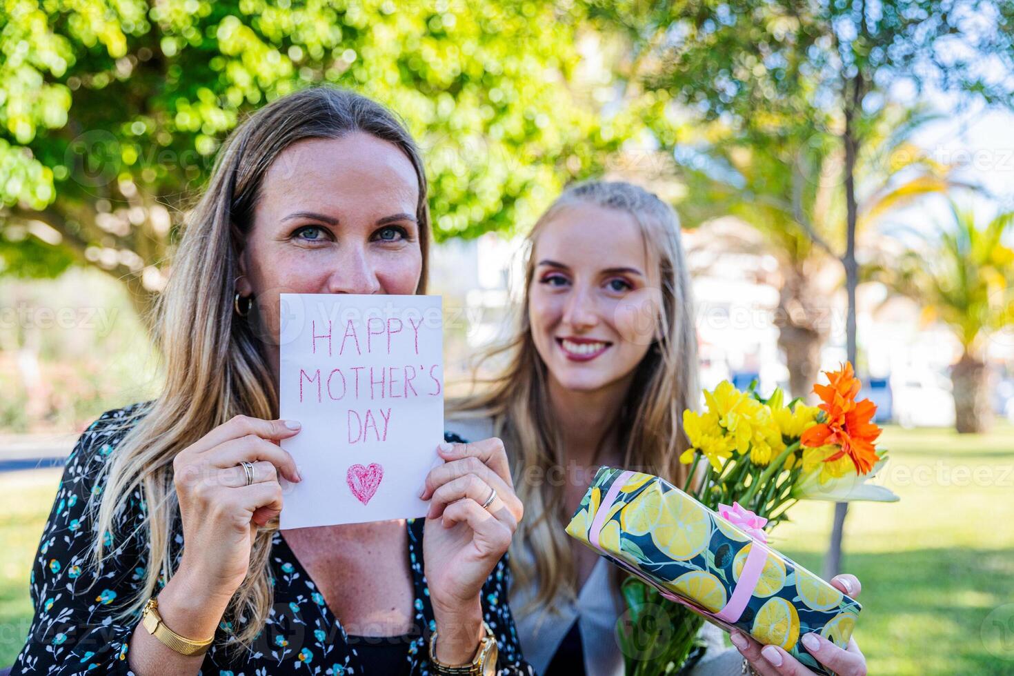Mother receives a card, gift and flowers from her daughter for Mother's Day photo