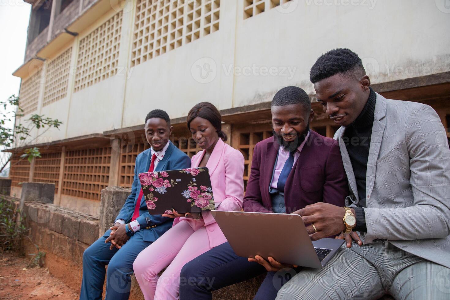 Four young adults work using their laptops and discussing job issues in Africa. photo