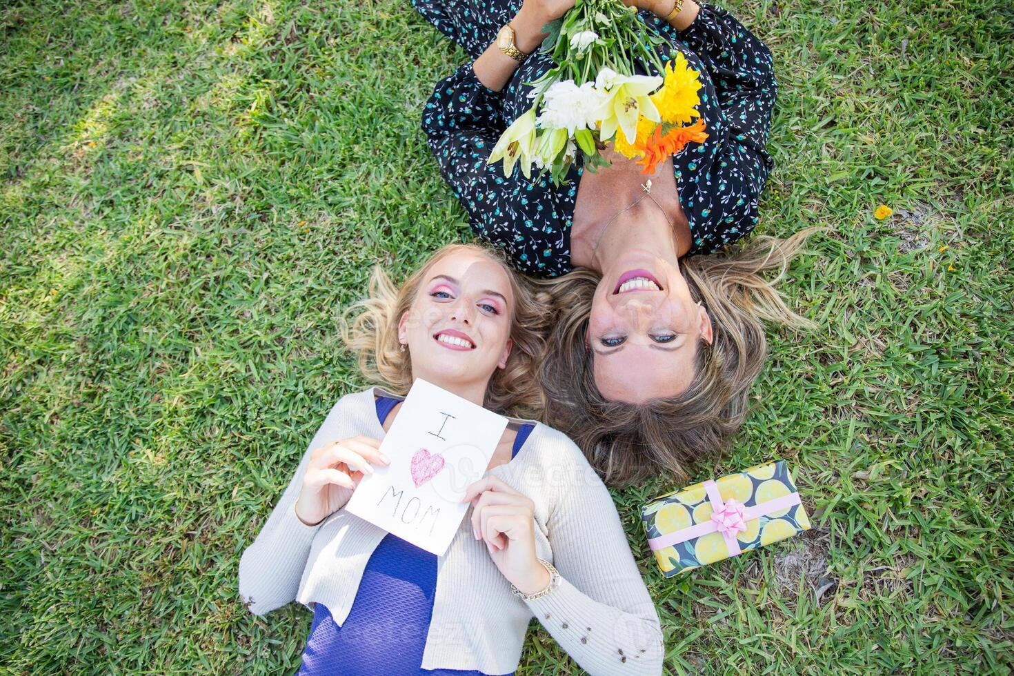 Daughter holding a card that says I love you mom while celebration her mother on Mother's day photo
